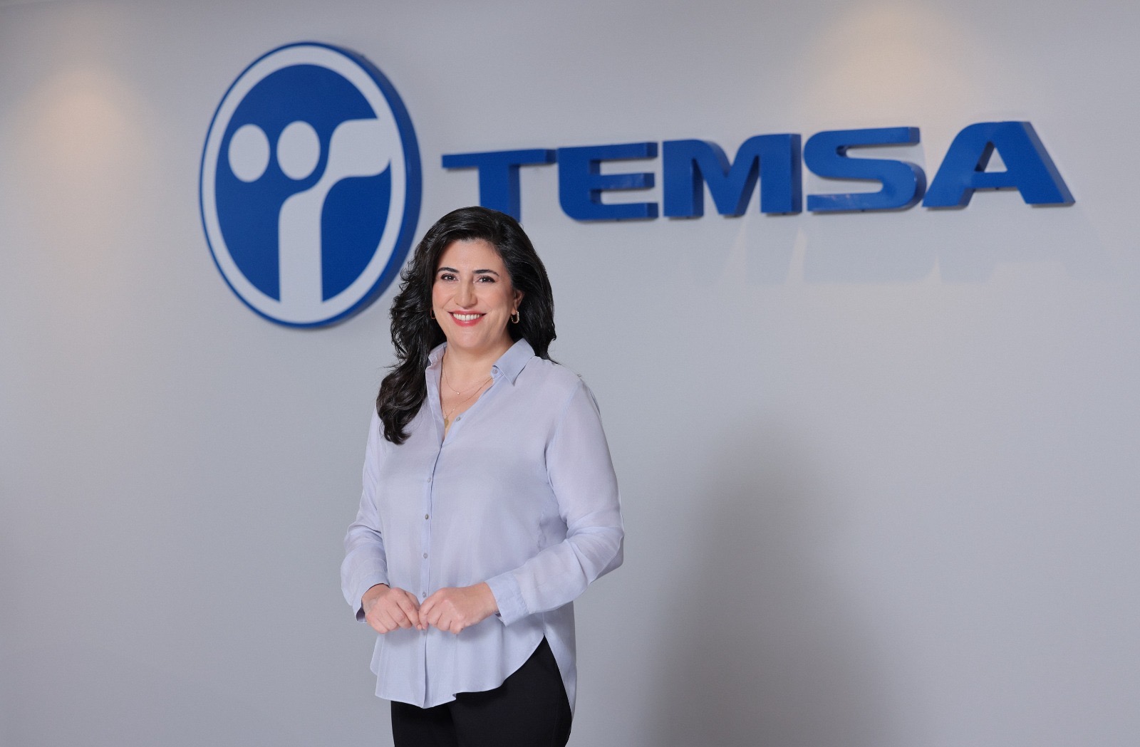 evren güzel temsa logosu önünde gülümsüyor